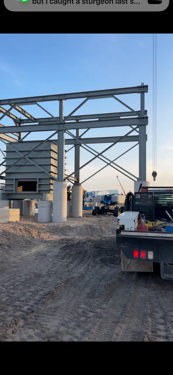 Steel frame structure under construction with work truck