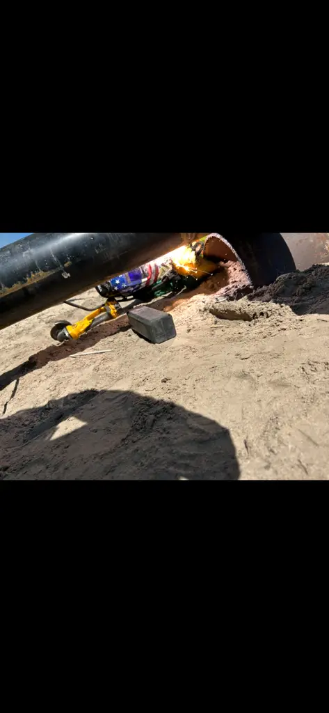 Welder welding under large pipe with bright arc