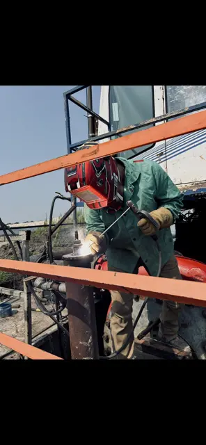 Welder stick welding on orange steel framework structure