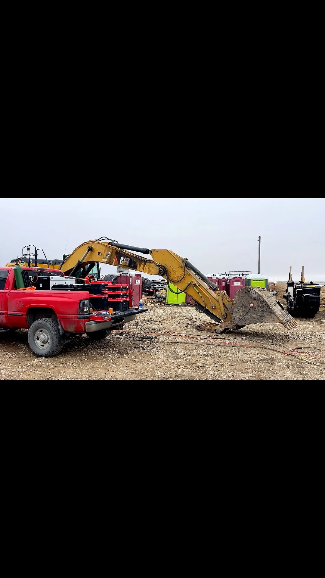 Red welding rig truck parked beside CAT excavator on job site