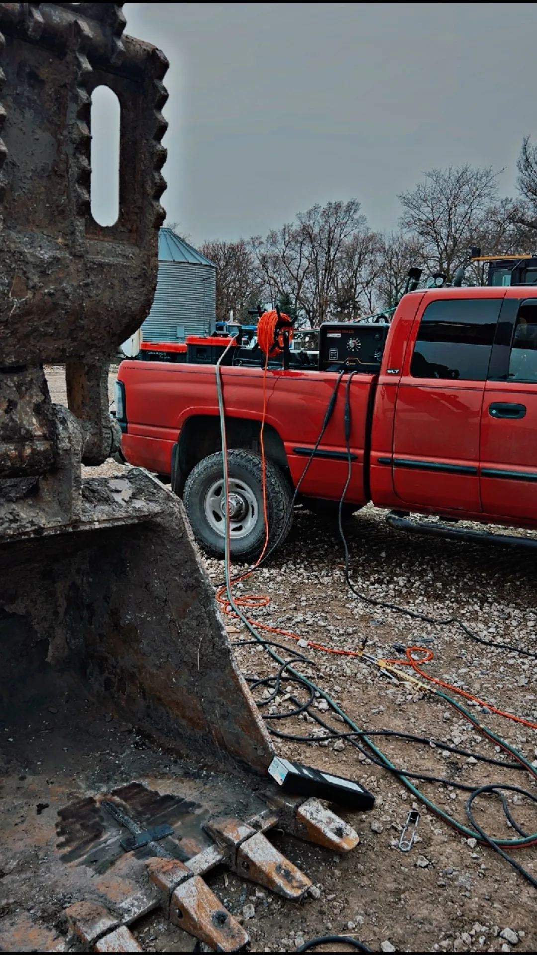 Mobile welding rig with leads running from truck to CAT excavator mid-repair